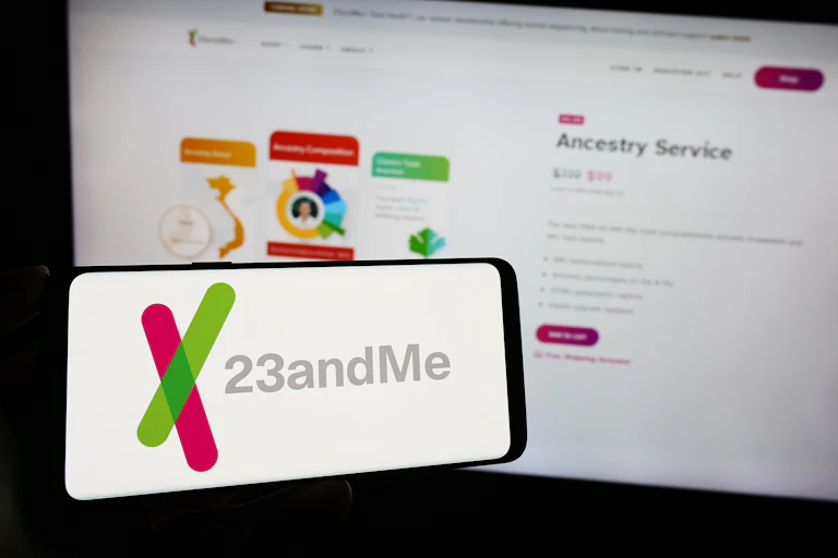 a computer screen and mobile phone screen both showing the 23andme logo and website