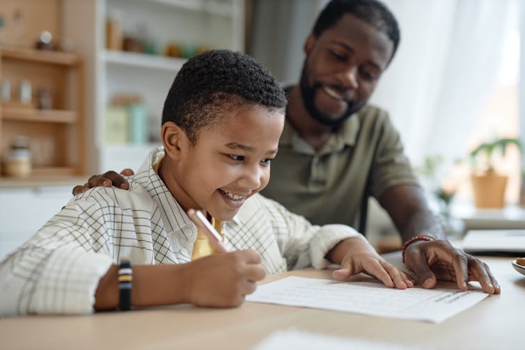 Man and son doing homework smiling