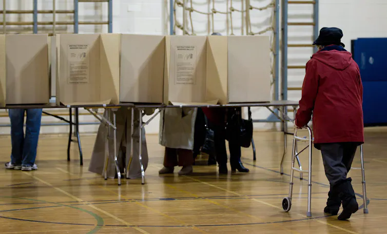 A woman using a walker walks toward voting booths in a polling station