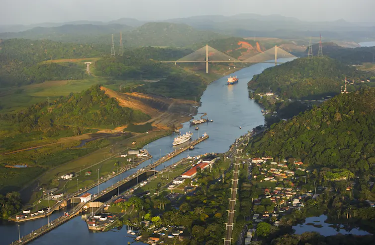 A view of ships on the canal, looking across green hills and fields surrounding it.
