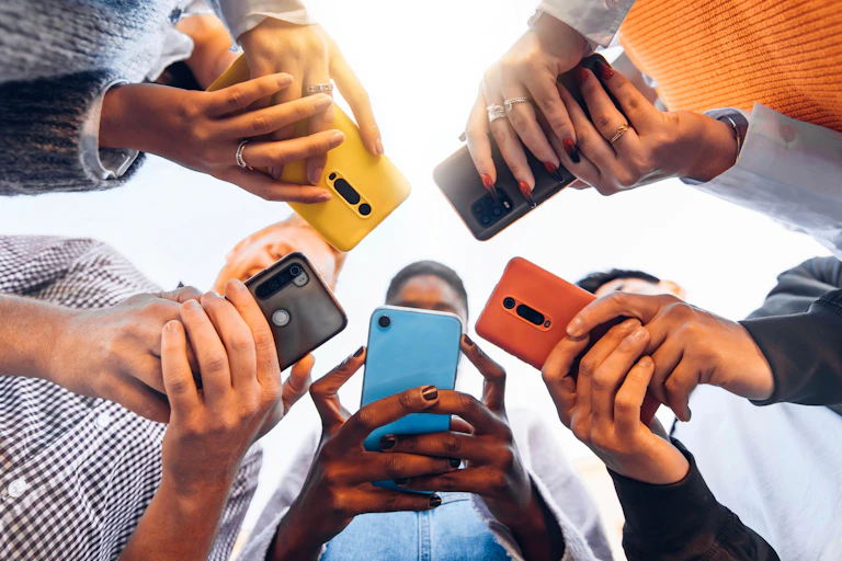 Teens in circle holding smart mobile phones