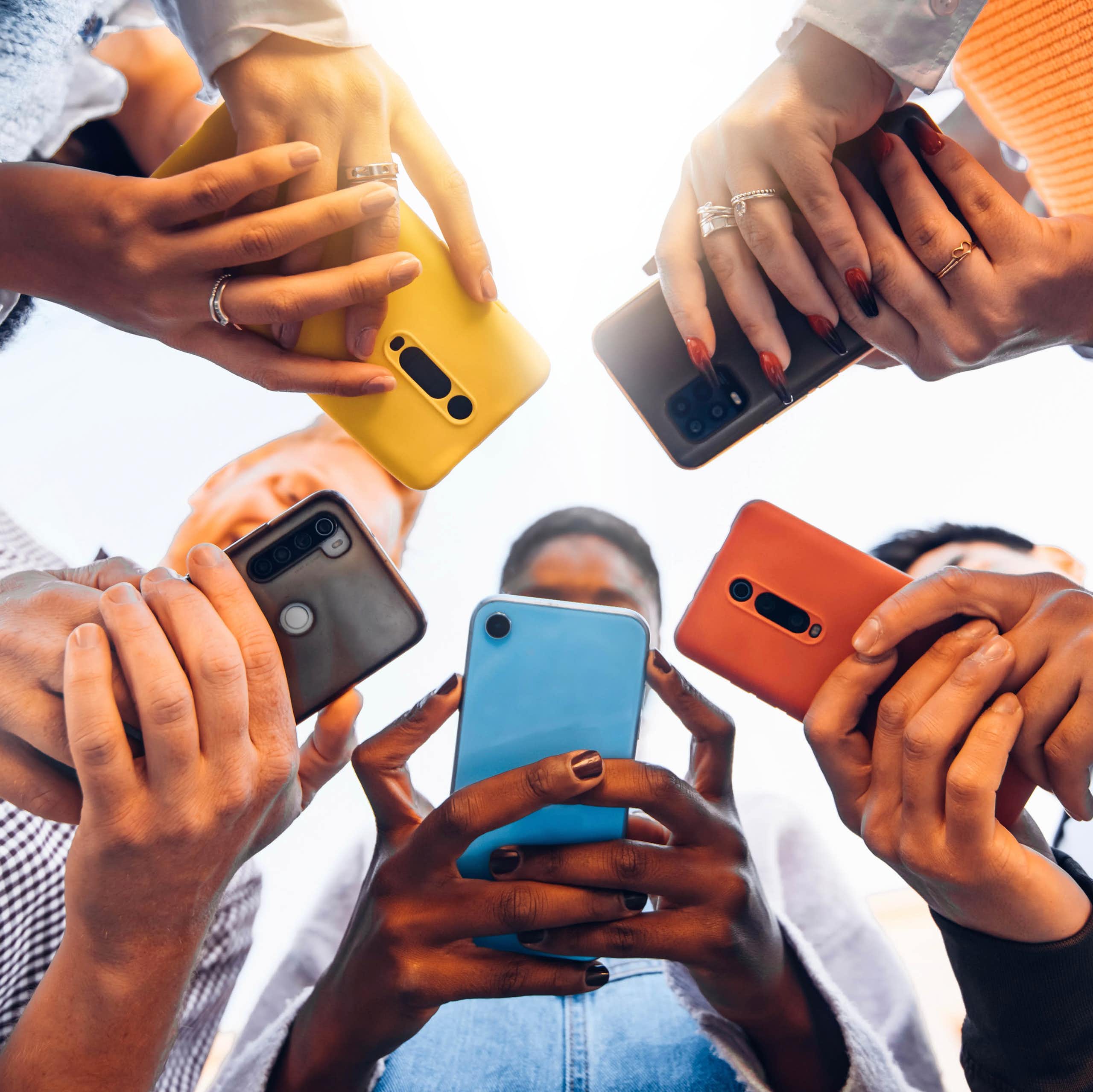 Teens in circle holding smart mobile phones