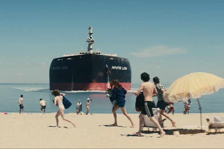 A huge tanker ship heading straight for a beach with people on it.