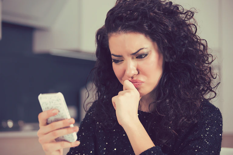 Woman looking concerned at phone screen.