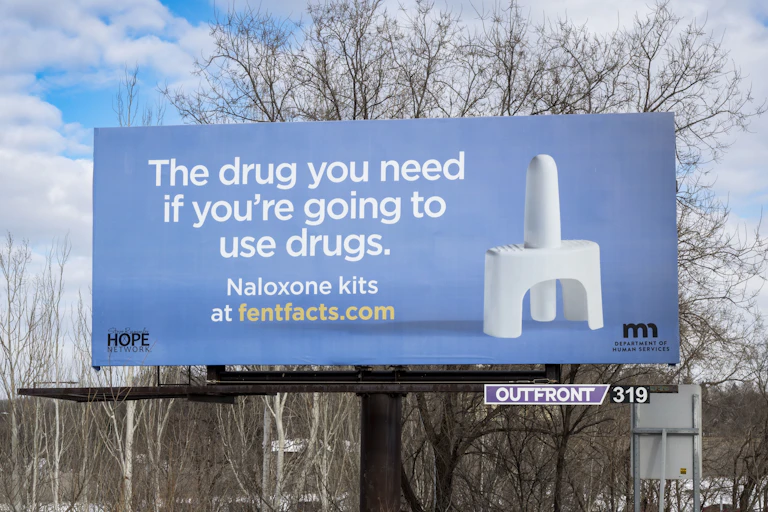 A billboard depicting a naloxone nasal spray device.