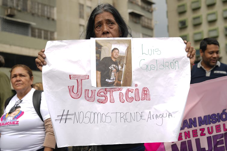 A woman at a rally holds a sign in Spanish that reads,