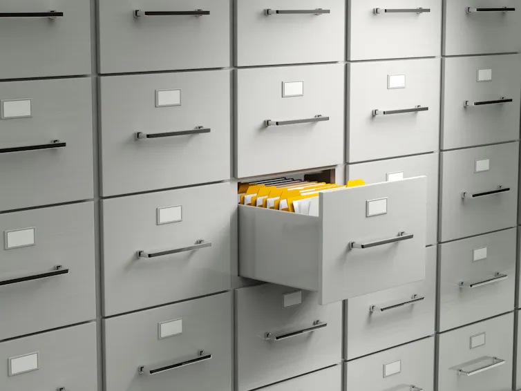 An open file drawer amid many shut file drawers.