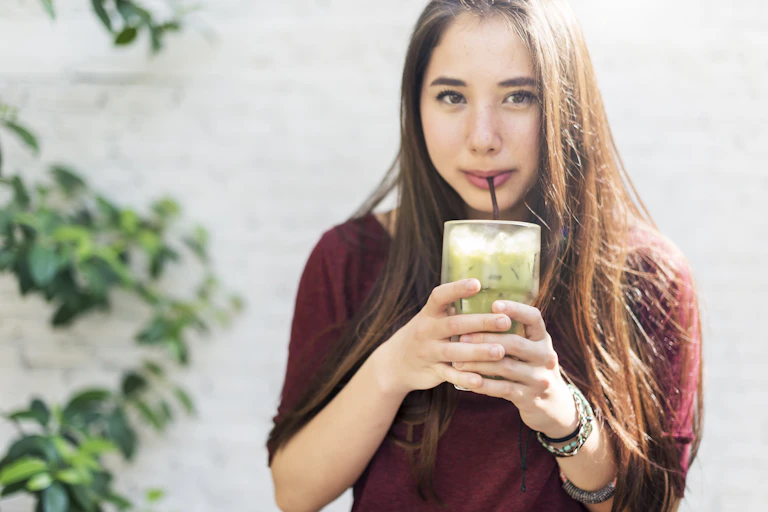 Uma jovem bebendo um matcha gelado.