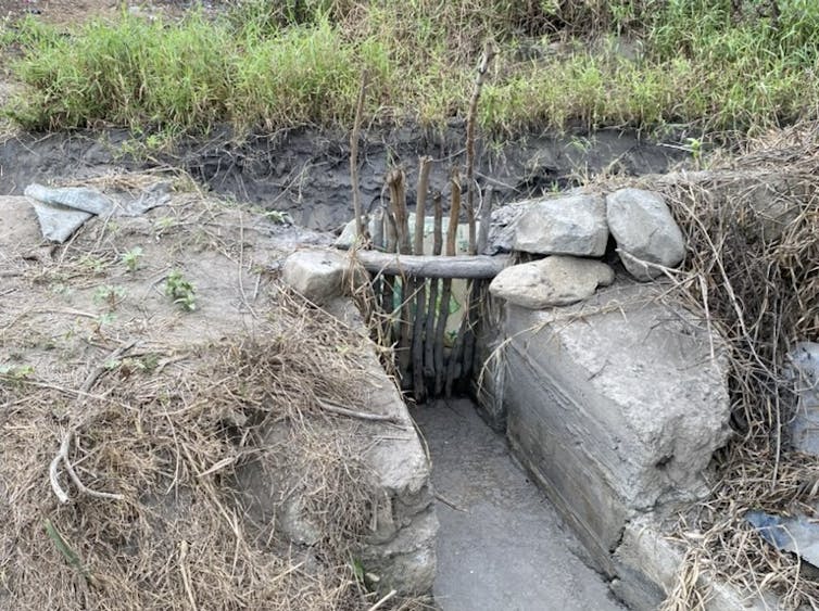 A canal with a gate made of pieces of wood.