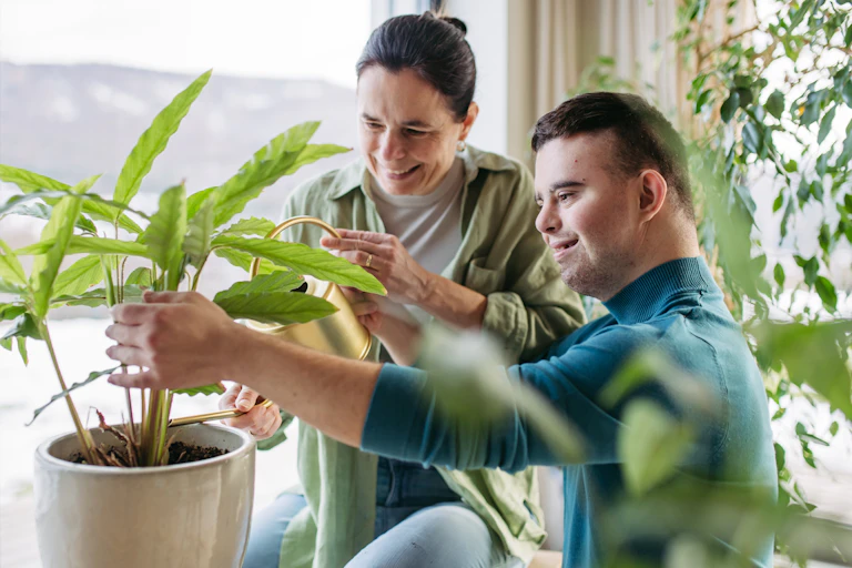 A woman and young man examine a plant in a pot