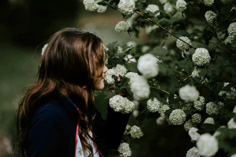 a long-haired girl smells a flower