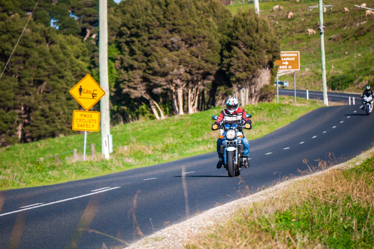 Front view of a motorcylist on a curving highway.
