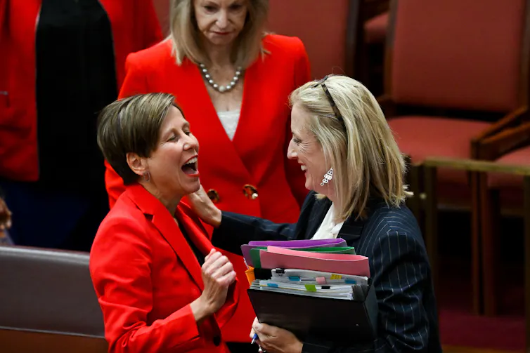 two women in suits embrace