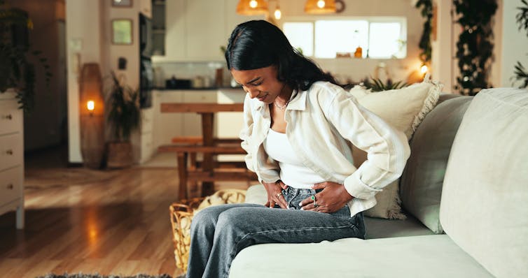 A woman clutches her stomach.