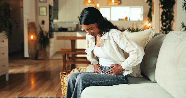 A woman clutches her stomach.
