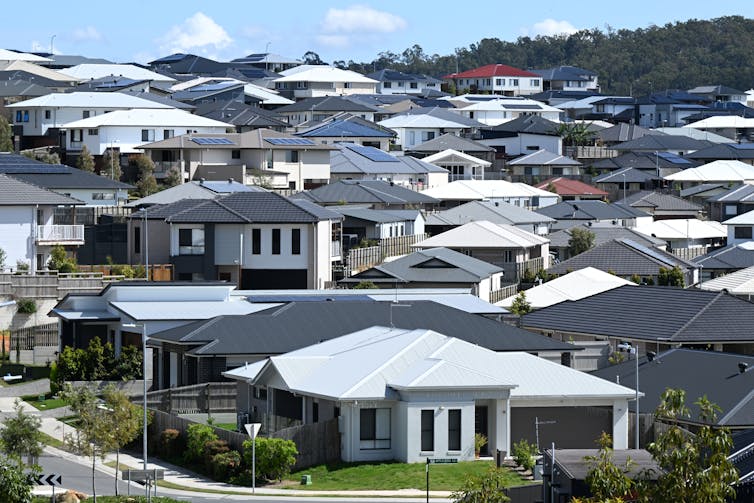 Dozens of houses, with white roofs and black roods, on a a sloping street