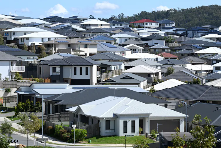 Dozens of houses, with white roofs and black roods, on a a sloping street