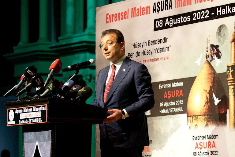 a man wearing a suit and glasses speaking at a podium