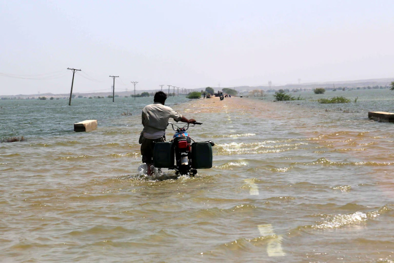 A person pushing a bike down a flooded motorway.
