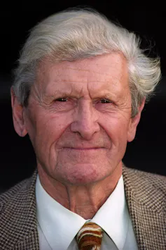 An elderly grey-haired gent dressed in a tweed jacket.