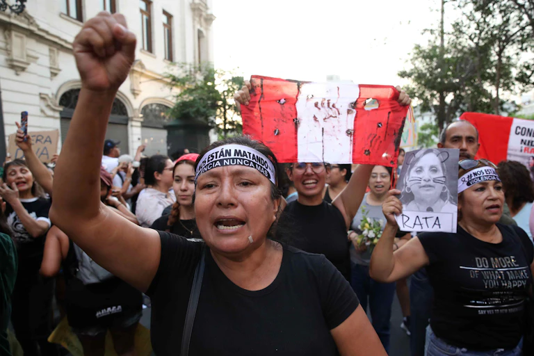 A group of demonstrators chant and wave banners at a protest in Lima, Peru.