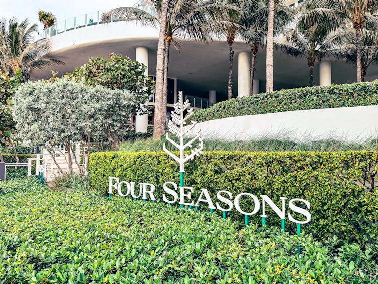 The Four Seasons hotel group signage next to a hedge.