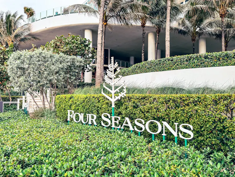 The Four Seasons hotel group signage next to a hedge.