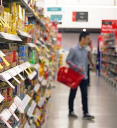 man browses supermarket aisle holding basket