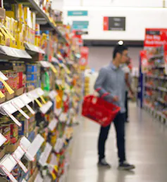 man browses supermarket aisle holding basket