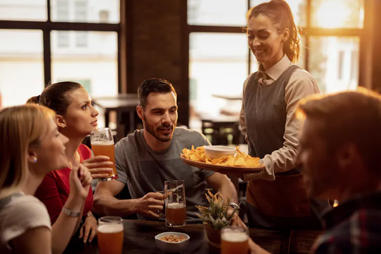Woman serving food to group of people sitting at table
