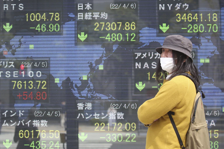woman in mask stands in front of screen showing stock values