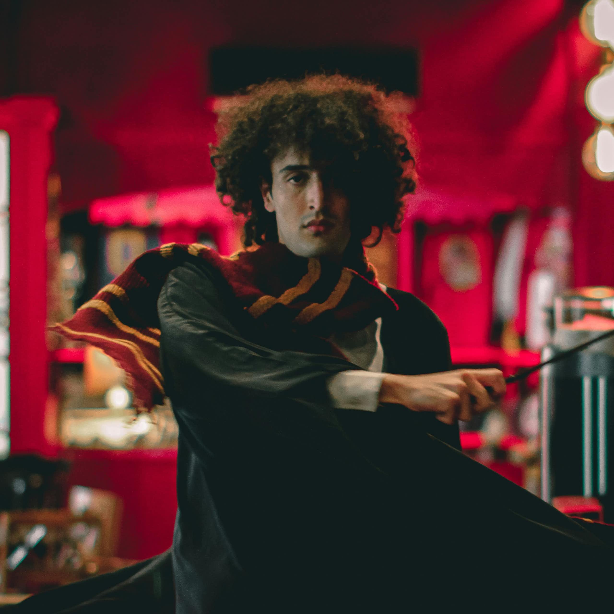 Un homme déguisé en sorcier tient une baguette magique.