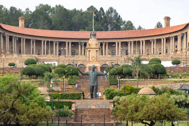 A curved building facade with terraced gardens and a statue of a man in the foreground
