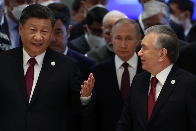 Xi Jinping and Shavkat Mirziyoyev walk ahead of Vladimir Putin.