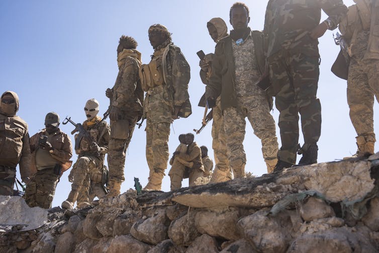 Soldiers stand around a military installation.