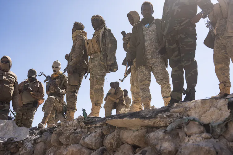 Soldiers stand around a military installation.