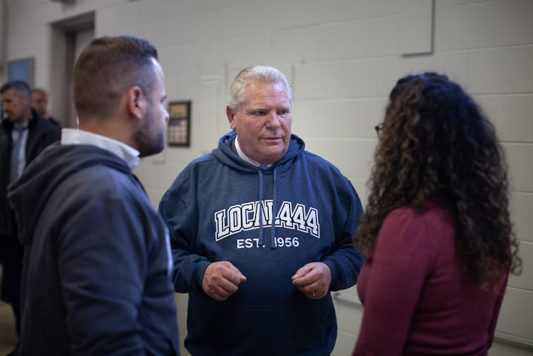 Man rotundo con conversaciones de jefe similares con personas mientras usa una capucha que lee Local 444.