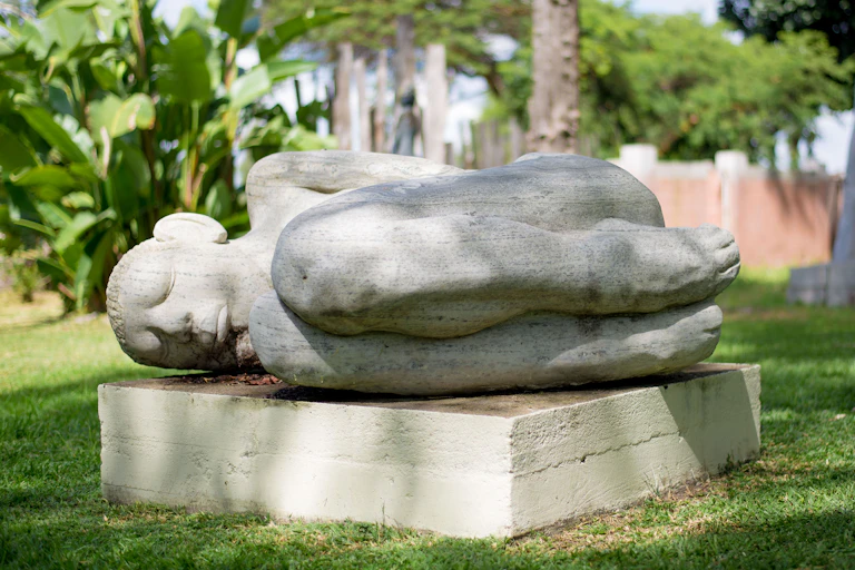A stone sculpture of a sleeping human figure, legs drawn up to its chest.
