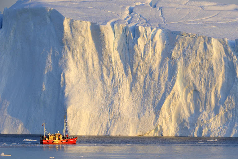 A ship in front of an iceberg, Disko Bay, Greenland.