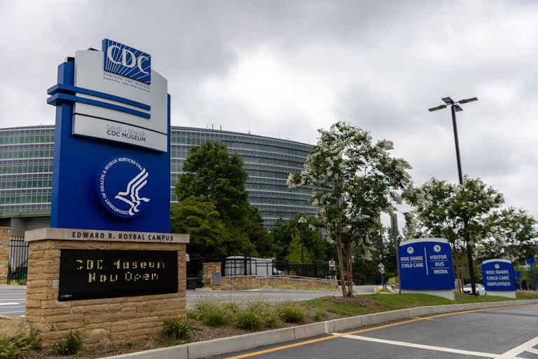 Outside view of the Centers for Disease Control and Prevention headquarters with sign in foreground and building in background.