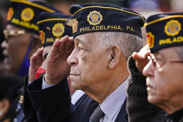 Four elderly men in military uniform salute