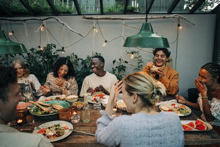 cheerful group laughing together around an outdoor dining table