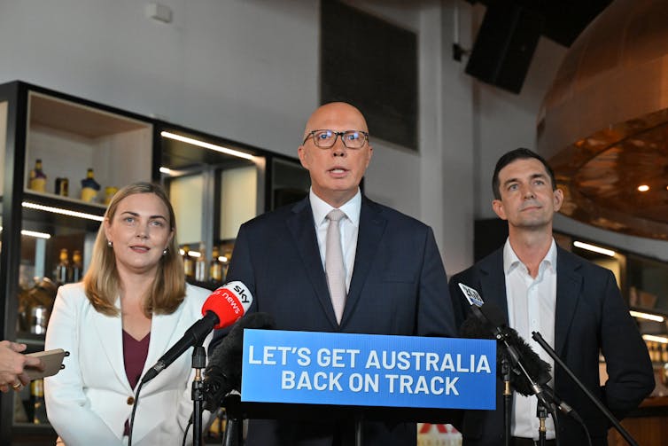 Peter Dutton speaks to the media at a lectern, flanked by male and female candidates.