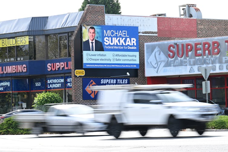 A blue billboard for a MP above passing traffic