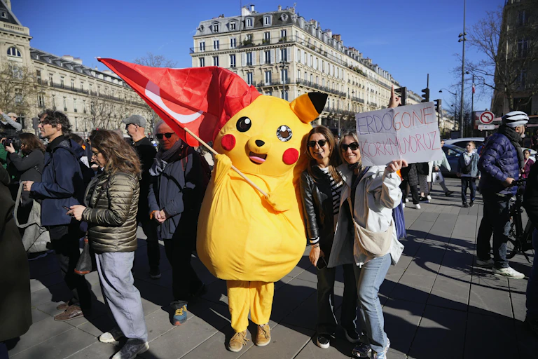 A person in a Pikachu costume waving a Turkish flag amid a group of protesters.