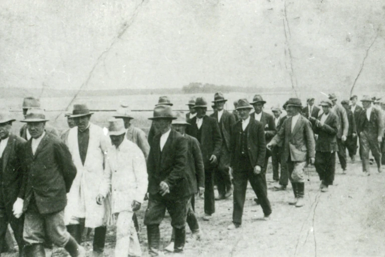 A black and white image of a protest march of rural workers on a dusty road in the 1930s.
