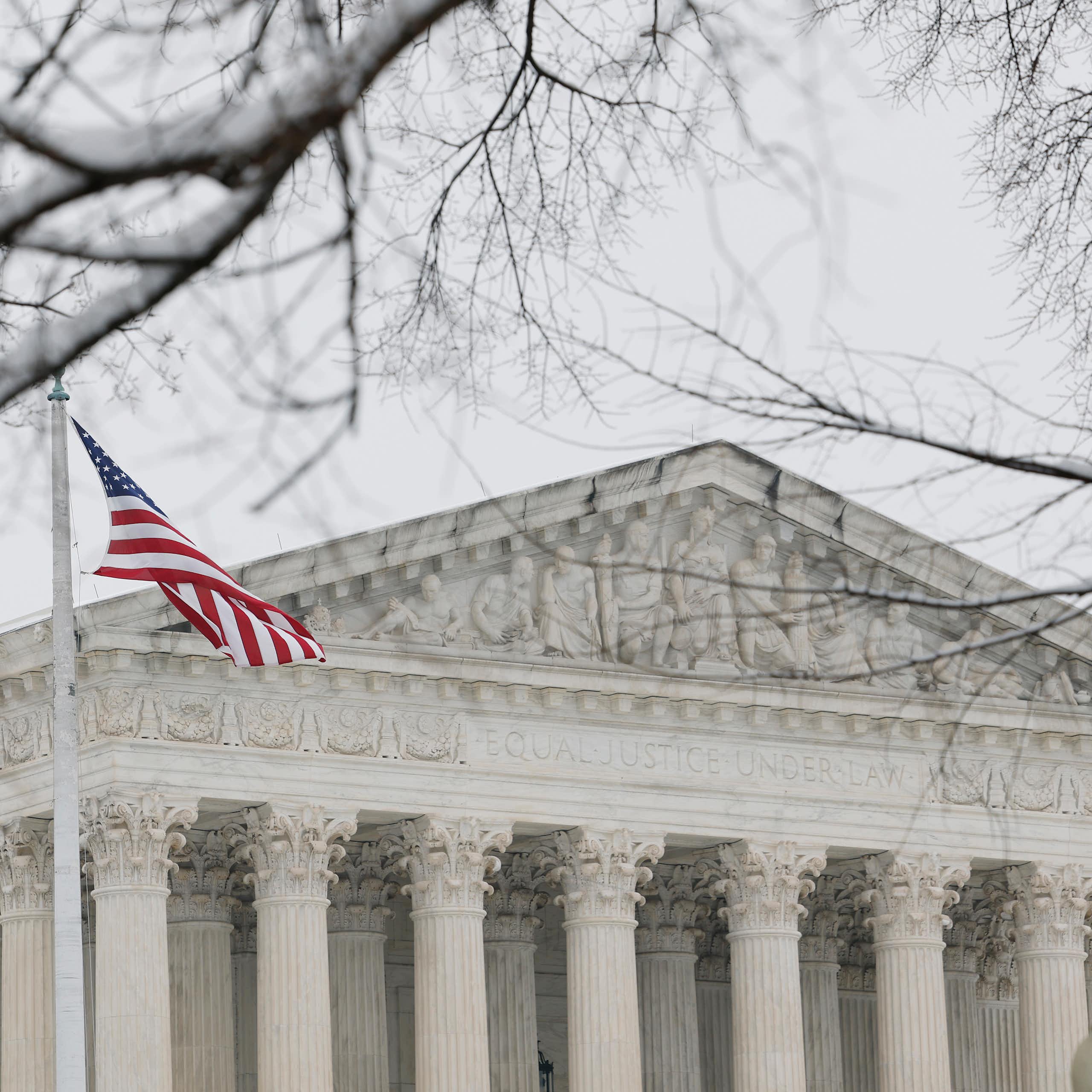 A large, white-columned building with a tree in the foreground.