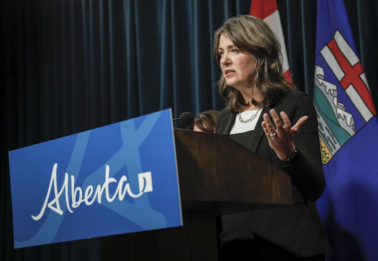 La mujer de patas oscuras habla desde detrƔs de Albert Lectern.