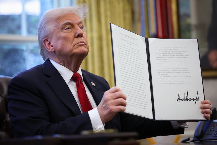 A man at a desk holds a document.