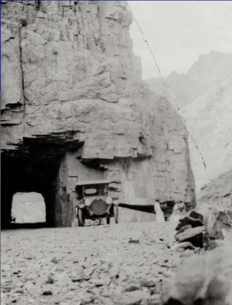 Early 1900s car traveling in the Rocky Mountains.